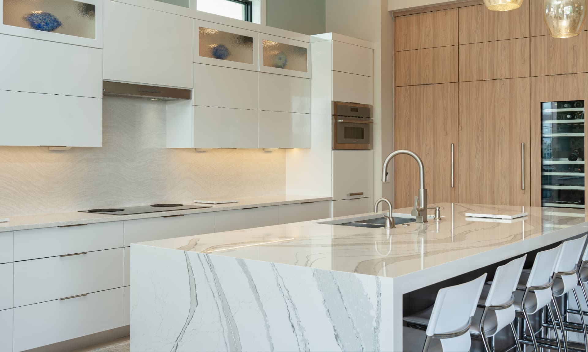 Kitchen with marble island, warm wood cabinetry, and tall white cabinets