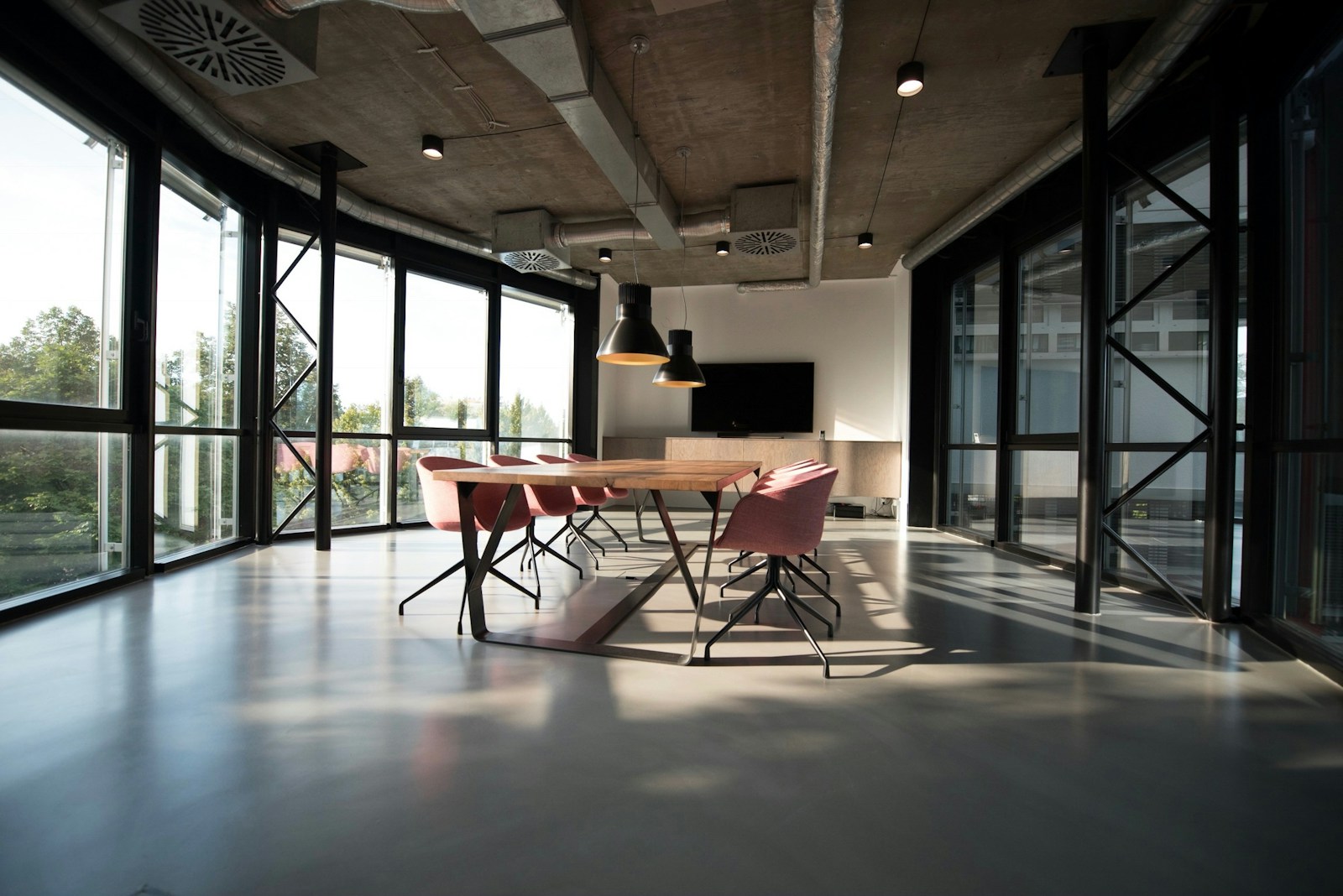 Temporary stock: glass-walled workplace with exposed concrete ceiling and a meeting area